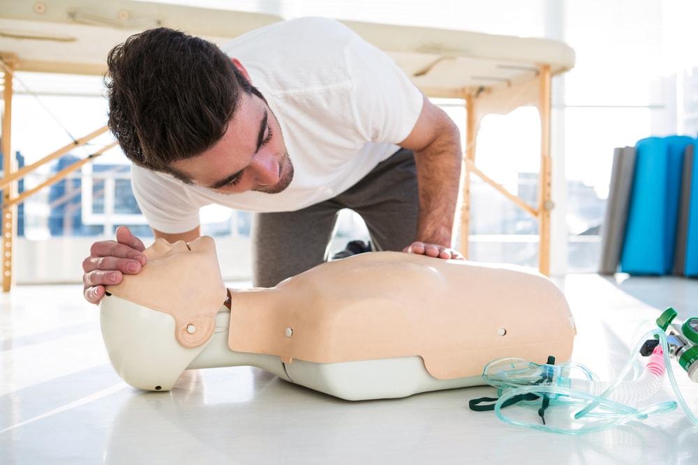 Paramedic training cardiopulmonary resuscitation to man in clinic