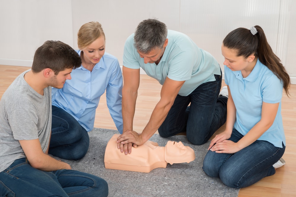 Mature Male Instructor Showing Cpr Training On Dummy To His Student